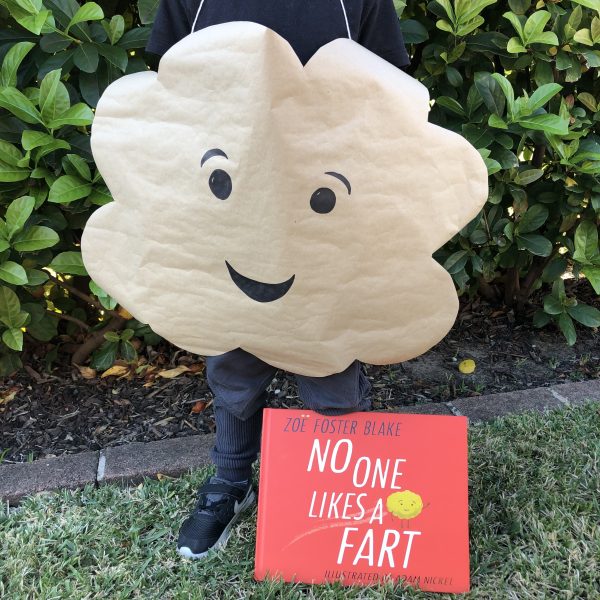 A cloud shape is cut out with a smiley face drawn on it and hung over someone's neck. The book No One Likes a Fart is also shown.
