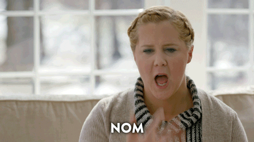 Gif of a woman licking her fingers and saying "nom nom nom nom nom"