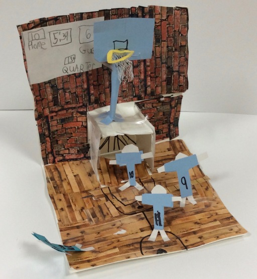 A basketball court scene is shown made from paper (second grade art)