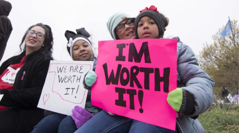 Girls holding up signs that say I'm worth it!- teachers poverty