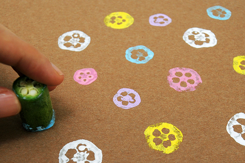 An okra is used as a stamp to make paint prints on brown paper.