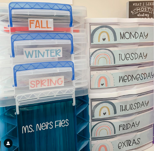 Plastic stacking bins labeled by season and a plastic rolling cart labeled by day