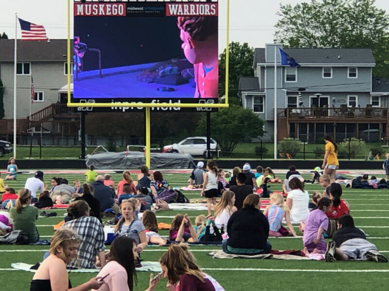 Students spread out on the football field to watch an outdoor movie