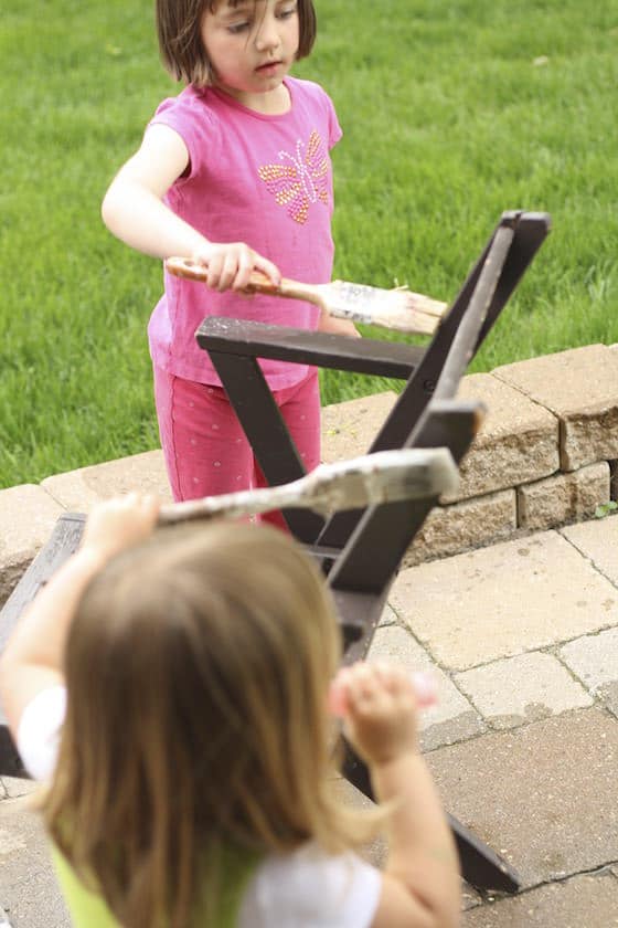 girl painting a chair with a paintbrush and water for a water activity