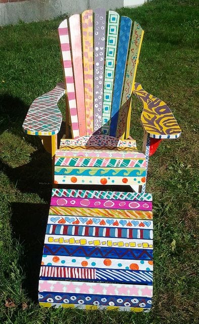 A classic Adirondack chair painted by a group of students with different colors and patterns