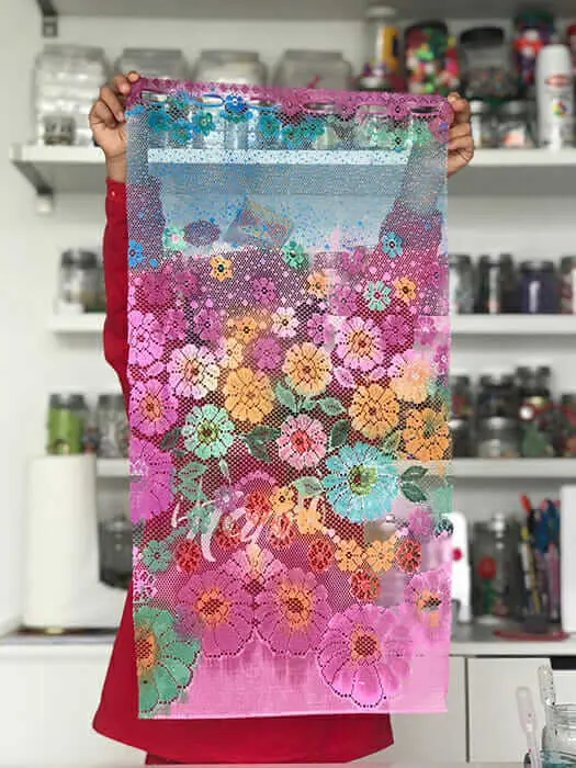 A child holds up a large piece of lace that has been painted with pastel colors. (mother's day crafts for kids)