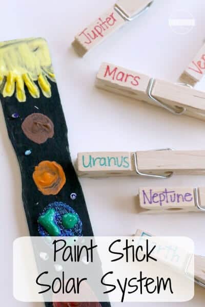 A wooden paint stick has been painted black with different colored planets painted on it. Clothespins are shown beside it with the names of planets on them (solar system projects)