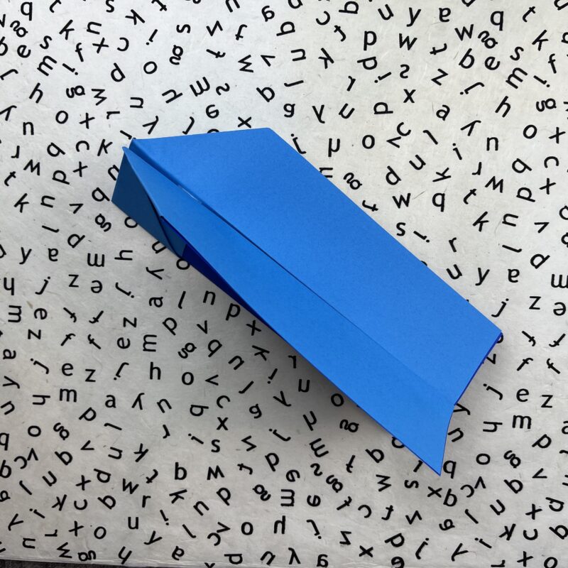 طائرة ورقية حيلة زرقاء على خلفية أبجدية بالأبيض والأسود.