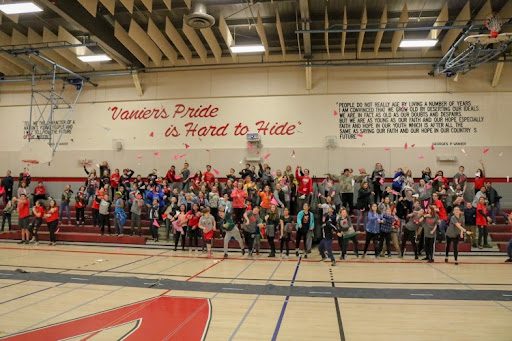 Students playing with paper airplanes in gymnasium