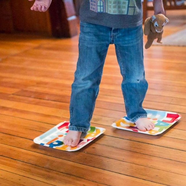 Boy skating on floor with paper plates under feet.