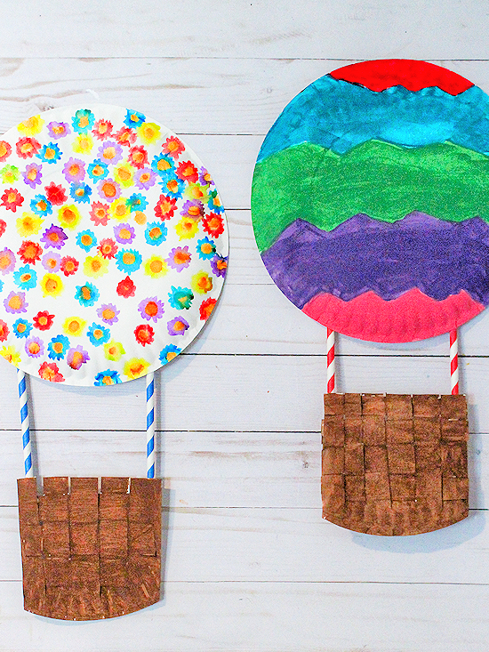 Two hot air balloons are shown. The top is made from decorated paper plates and they are attached to the base using straws.