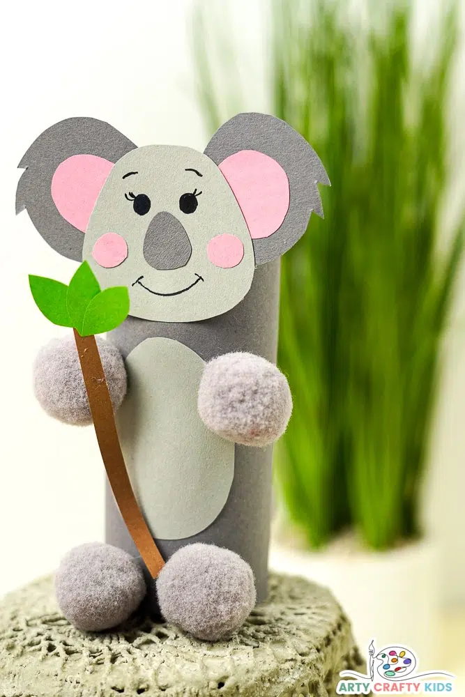 This easy art project for kids shows a cute koala made from a paper roll, construction paper, and pom-poms.