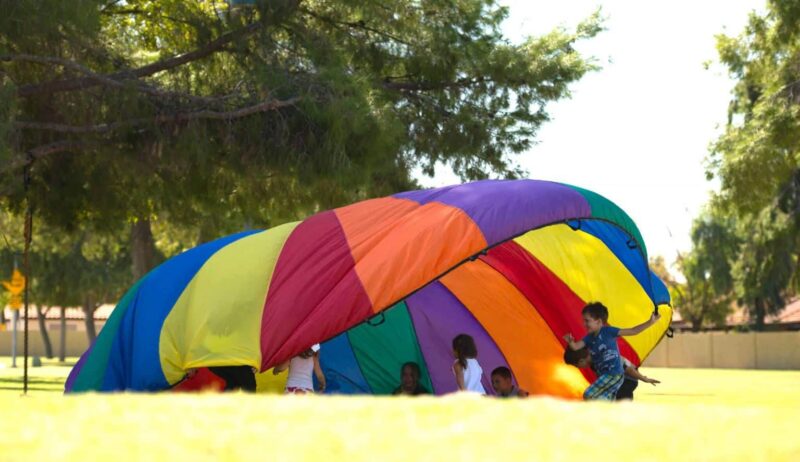 kids playing under a parachute for a fun friday activity