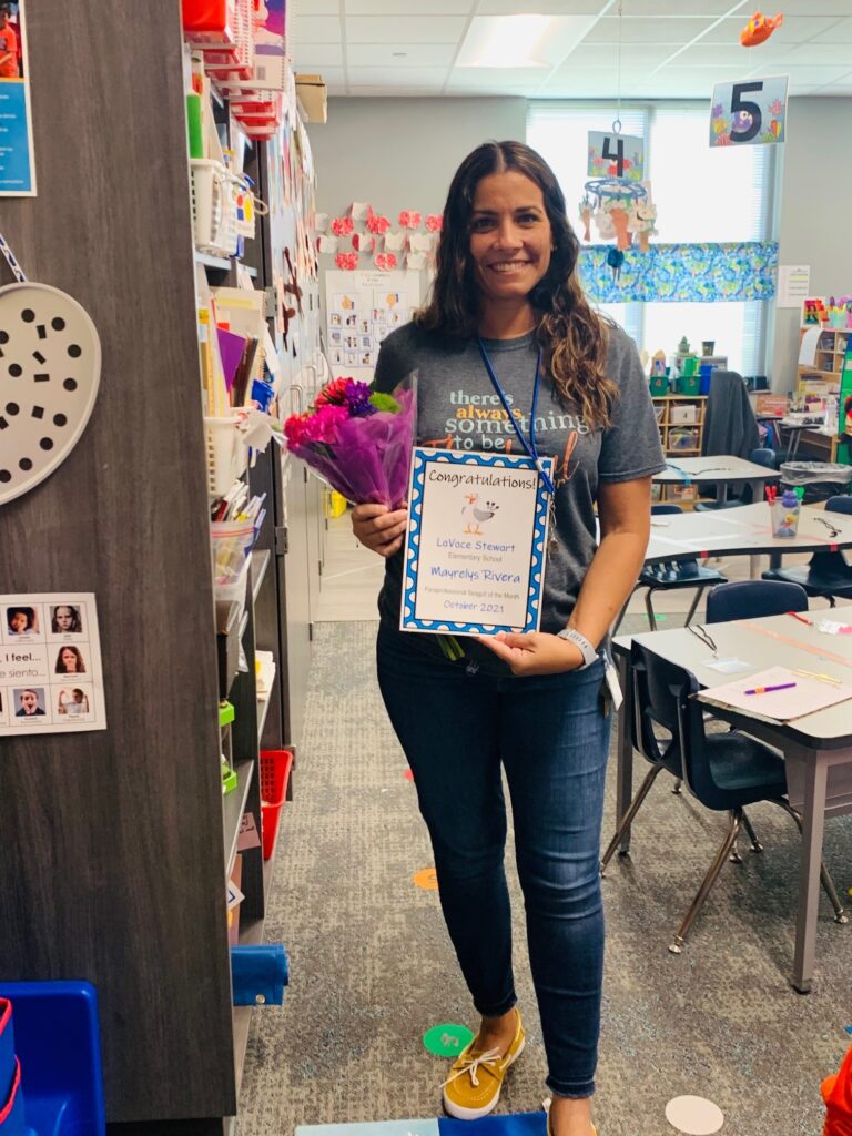 woman standing with a sign of recognition in a classroom