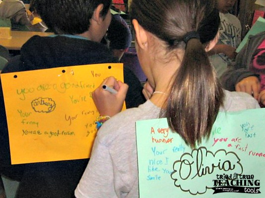 Students write compliments on sheets of paper taped to each other's backs as an example of fun last day of school activities