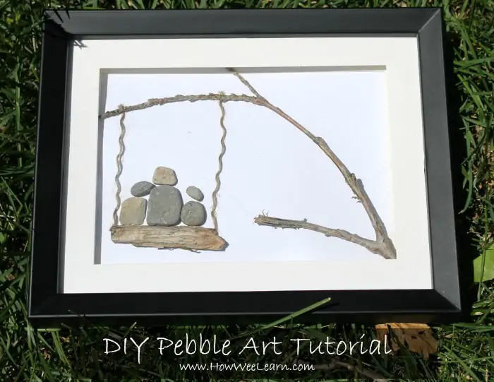 An arrangement of pebbles and sticks creates a picture of a swing on a tree