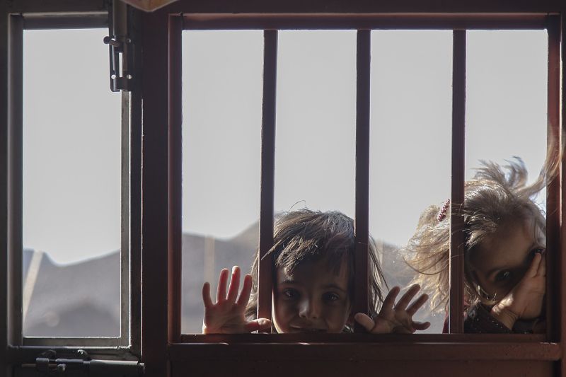Two children peering in through a barred window