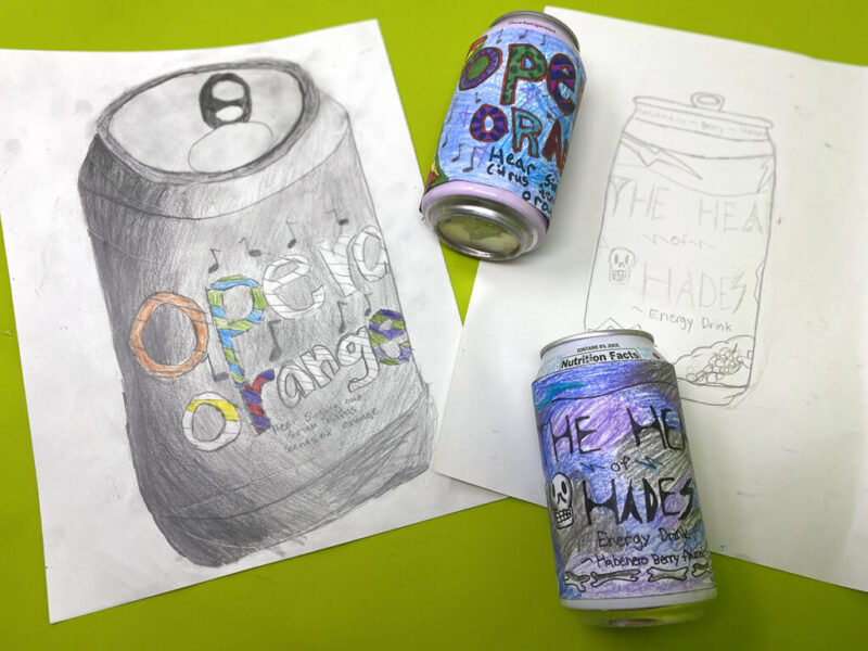 Two actual soda cans are covered in labels that have been drawn on by students.