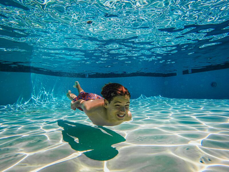kid swimming under the water in a pool for a summer job idea for teachers 