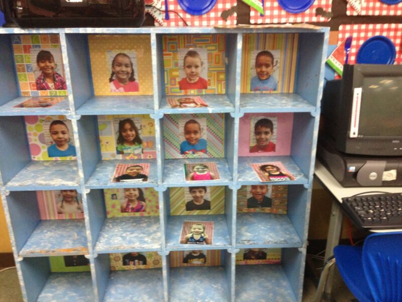Blue wooden classroom cubbies each have a photo of a different student in them.