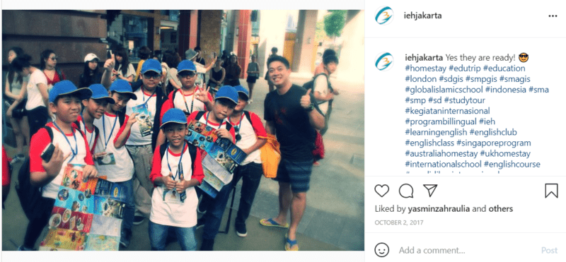 Teacher with students wearing red and white shirts and blue hats on streets of Jakarta