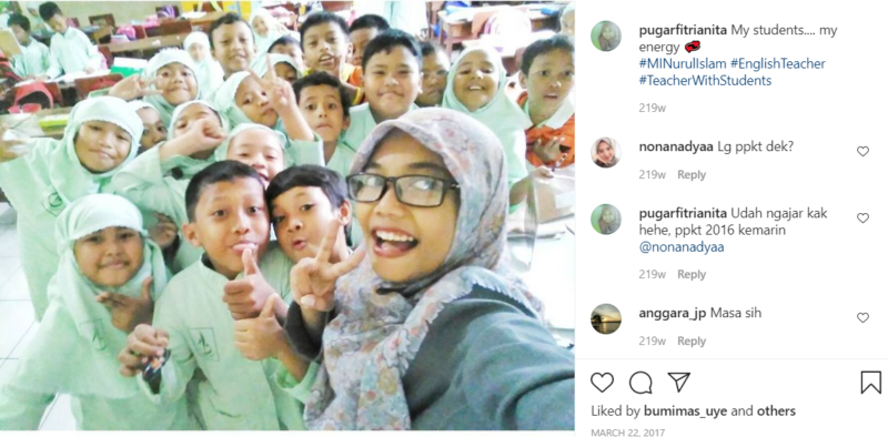 Teacher wearing glasses taking selfie with students in green uniforms