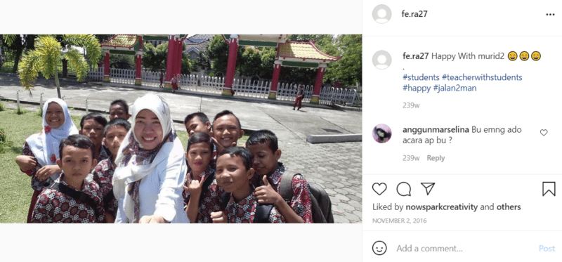 Teacher wearing white taking selfie with students outside school in Indonesia
