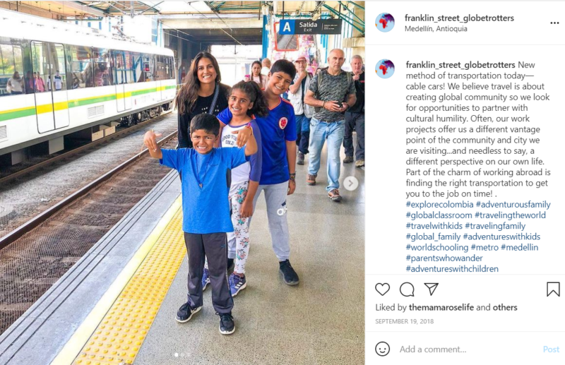 Teacher and students in blue shirts standing on train station platform