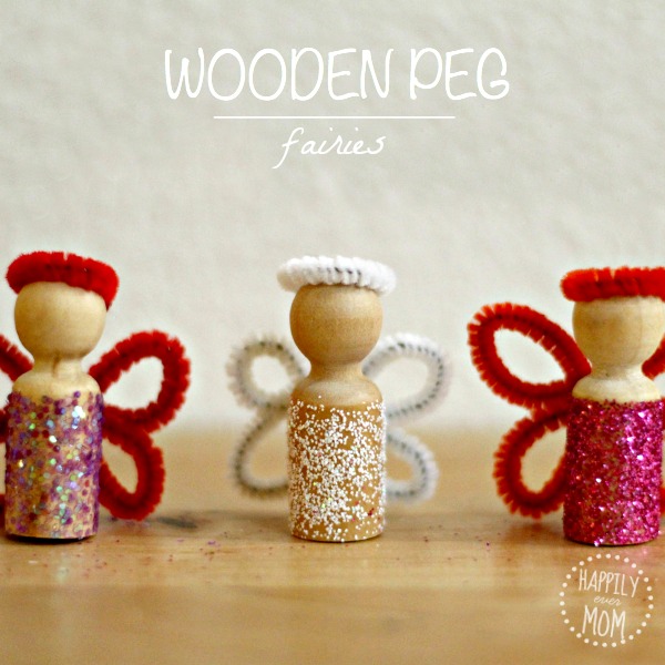 Three little wooden peg dolls are covered in glitter and have pipe cleaner wings and halos.