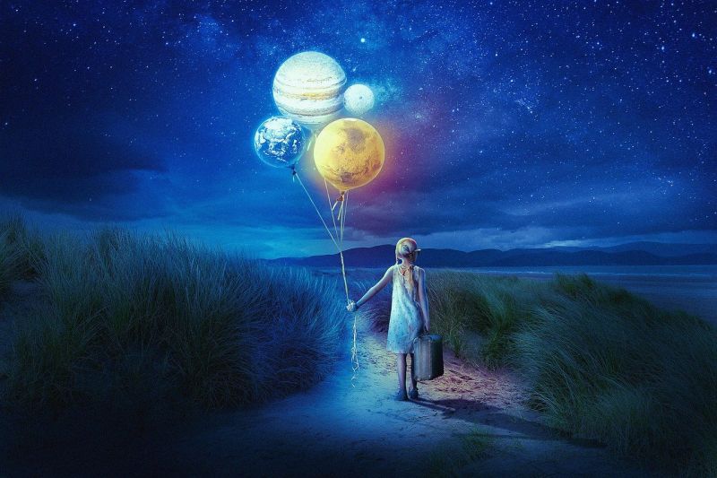 A girl standing on a path, holding a suitcase and a bunch of balloons that look like planets