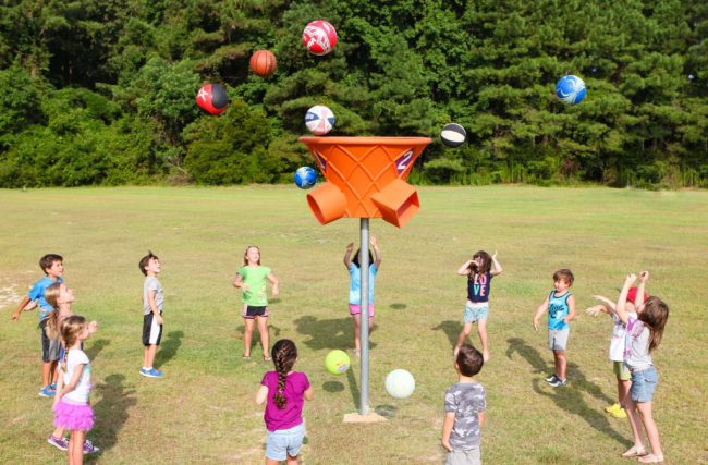 Children throwing balls into a large funnel with three openings for the balls to emerge from (Best Playground Equipment for Schools)
