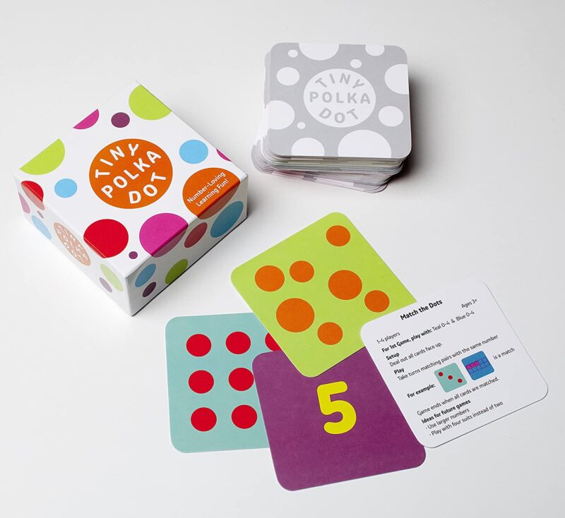 A white box has brightly colored polka dots on it and says Tiny Polka Dot. There are several cards shown in different bright colors with different numbers and number of polka dots on them (math board games)