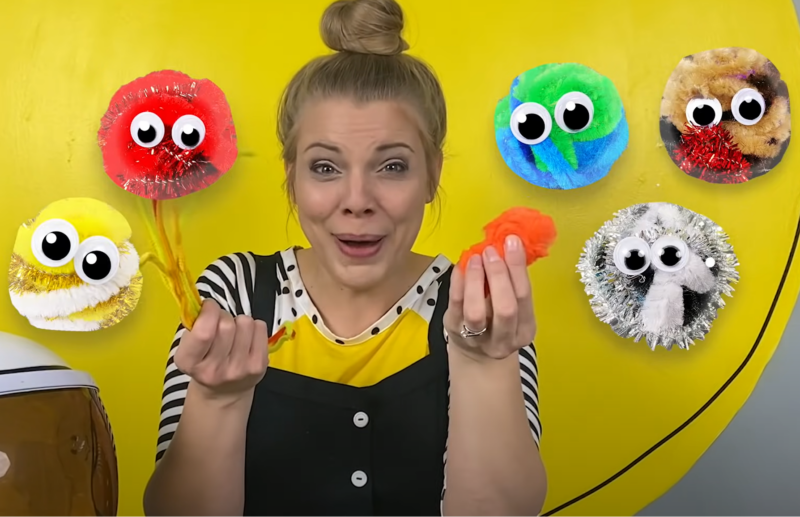 Woman holding pom-pom planet crafts.