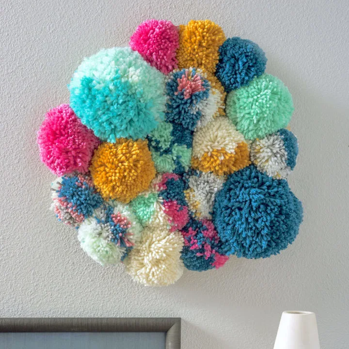 A colorful arrangement of hand made pom-poms as a wall hanging as an example of school auction art projects