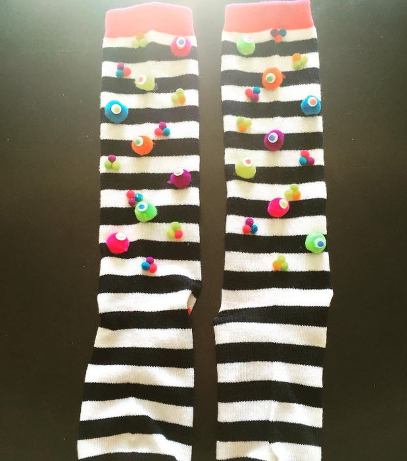 Black and white striped socks with colorful pom poms attached