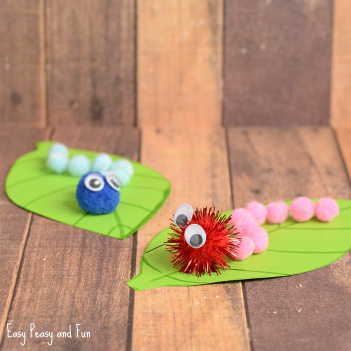 Two caterpillars are made from pom poms and sit on construction paper leaves.