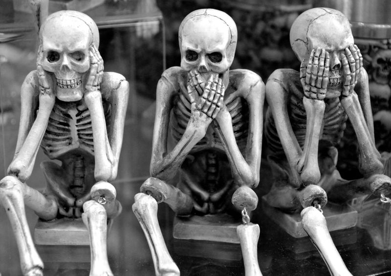 Three skeletons posed in the classic 