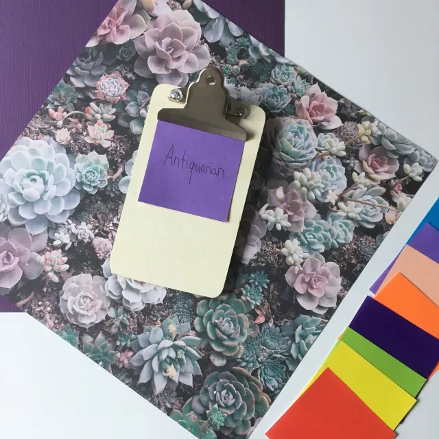a small clipboard with a purple post-it note attached on top of a floral backdrop