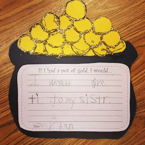 a pot of gold and coins made from black and yellow construction paper with a child's writing sample attached to it