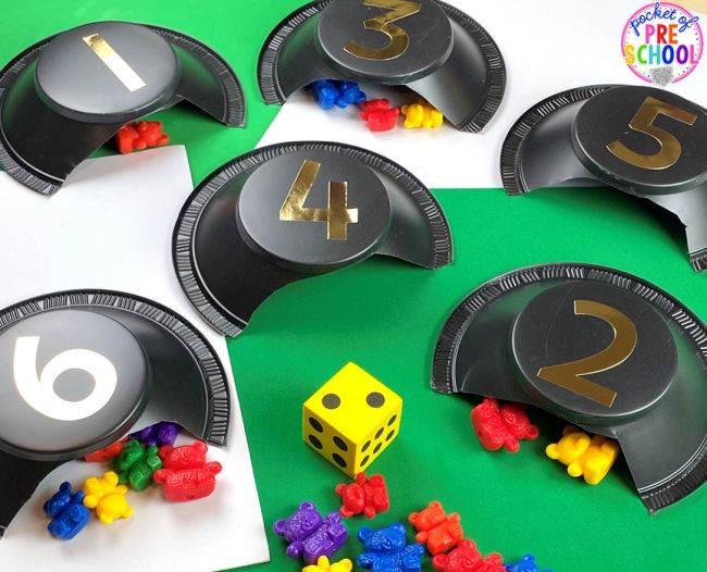 Small toy bears tucked into caves made from plastic bowls labeled with numbers (Preschool Math Games)