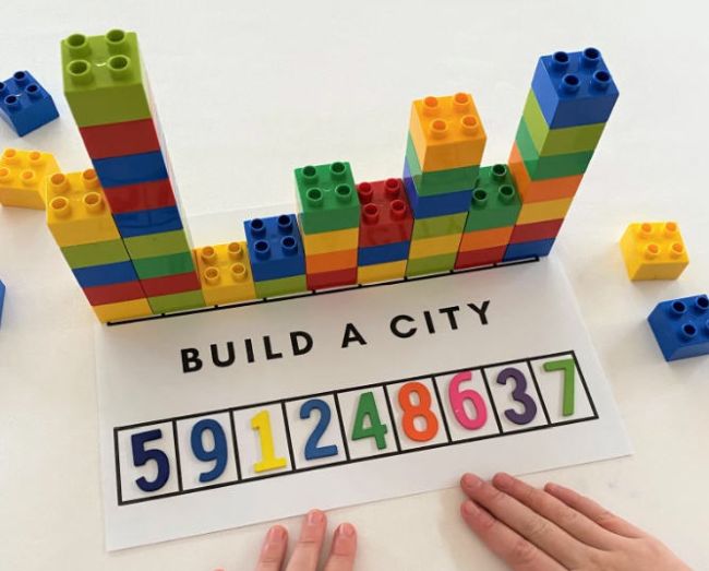 Student building towers of blocks to match number beads; text reads "Build a City" (Preschool Math Games)