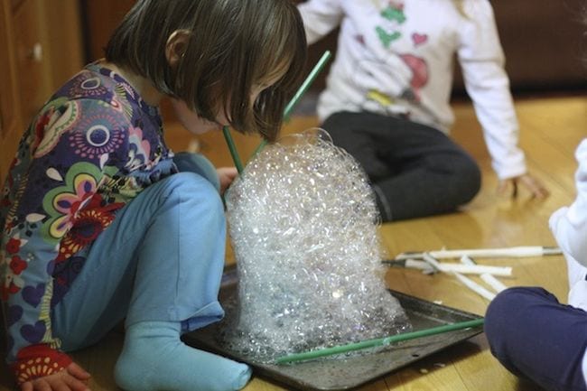 Preschool science student blowing a tower of soap bubbles