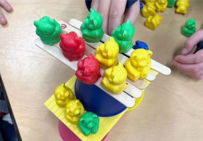 Toy bears stacked on plastic cups, wood craft sticks, and index cards