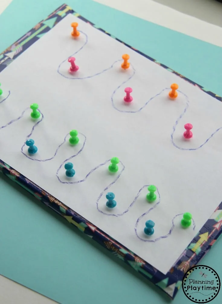 A piece of paper is shown with push pins in it and a crayon has been used to trace around the push pins (fine motor activities)