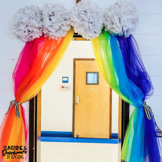 Rainbow scarves and white pompoms form a kindergarten doorway