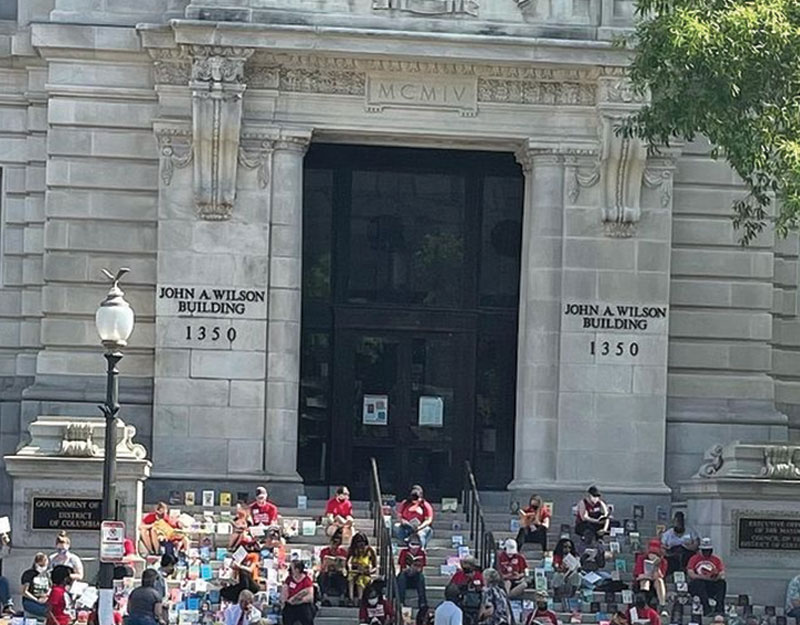 librarians sitting on steps of a building reading 