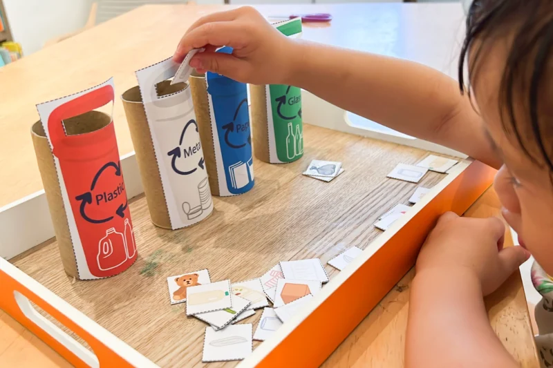 child sorting pictures into paper plastic and other materials 