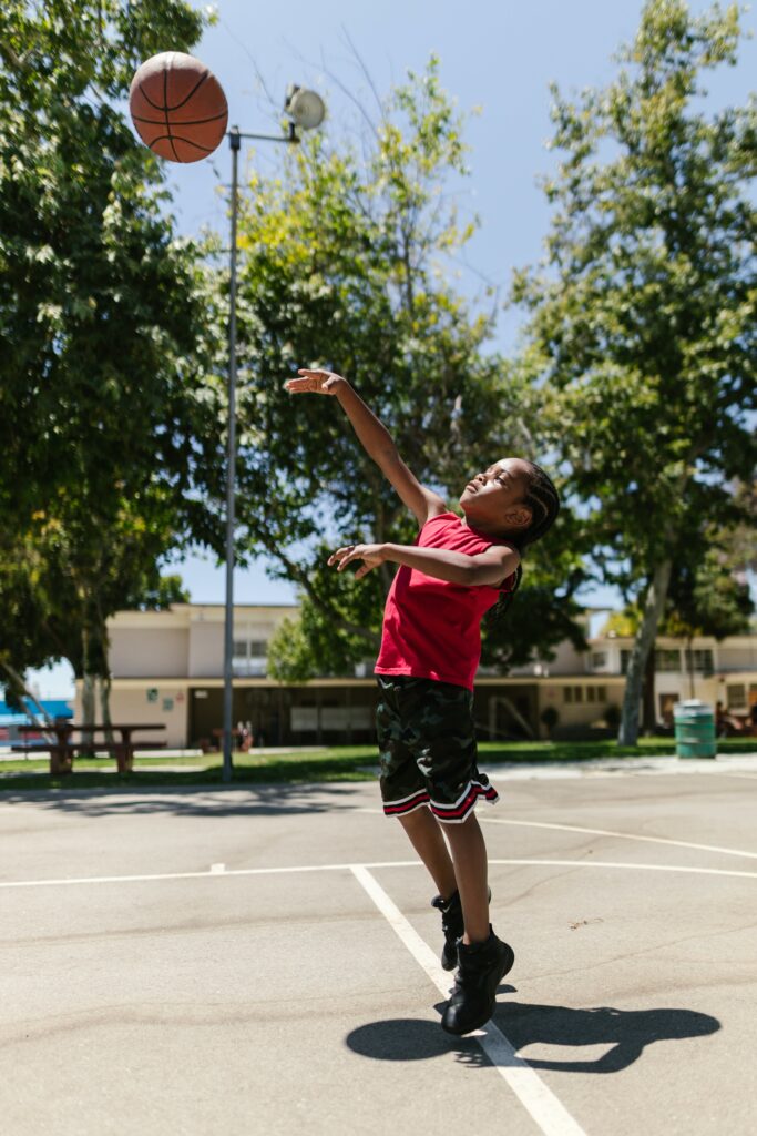 Child playing basketball in a red shirt to illustrate what is redshirting