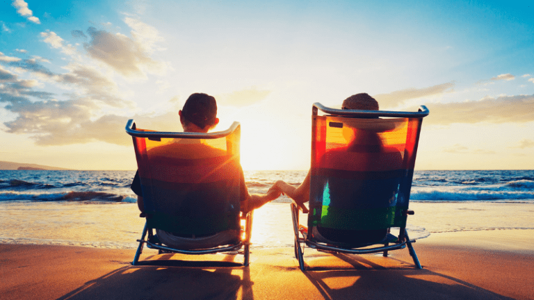 back view of retired couple in lounge chairs at beach watching the sun set after they used the retirement planning checklist