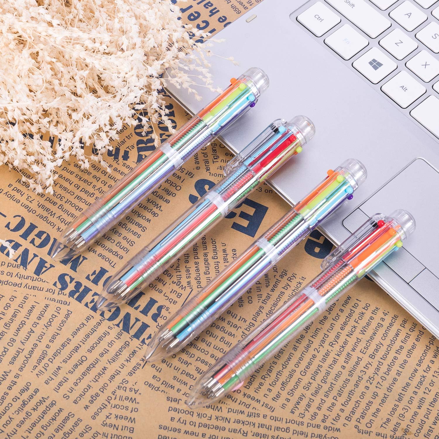 Four retractable multicolor pens next to laptop.